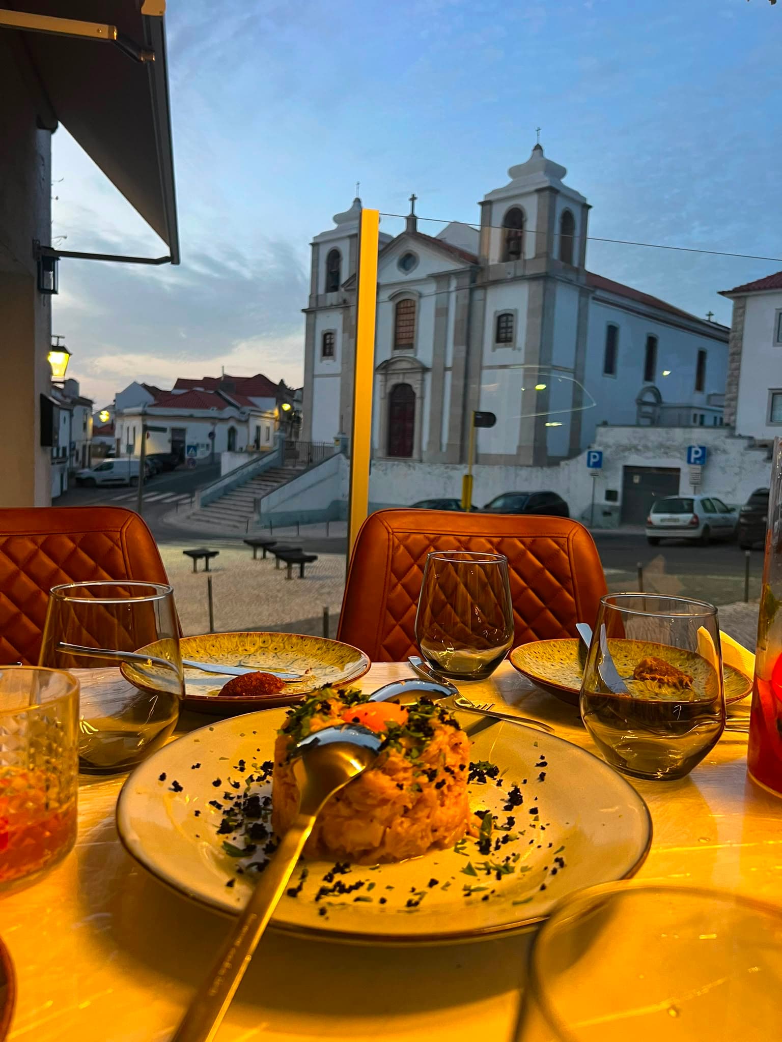 Copos de vinho ao anoitecer, à janela, com vista sobre a igreja de Palmela