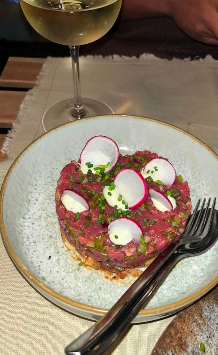 Tártaro de novilho servido com um copo de vinho branco