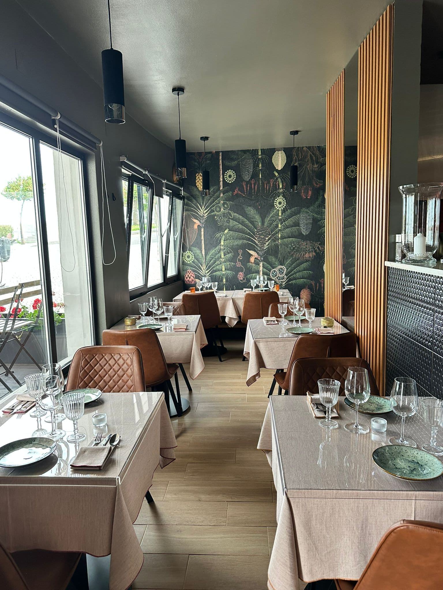 A sala de jantar da KAYA, com mesas postas e o painel botânico